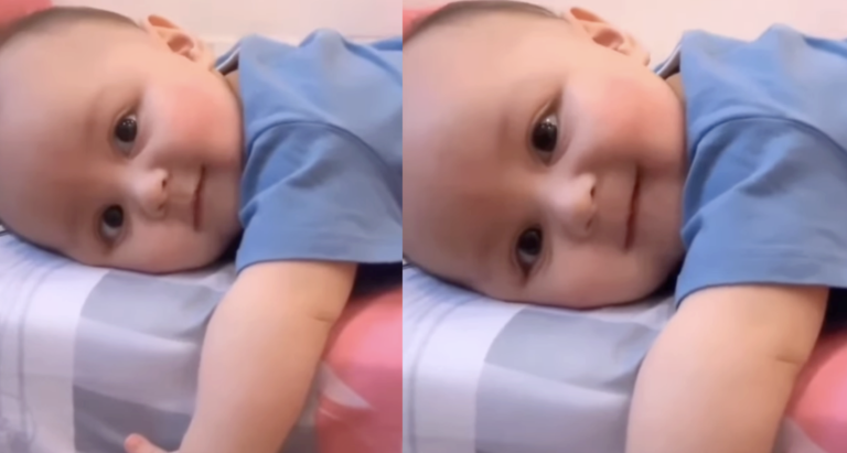 The Child Is Lying In Bed And Smiling So Cute