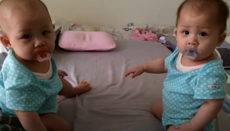 Twin Crystal can’t get her sister’s pacifier and ends up angrily throwing her hands up.