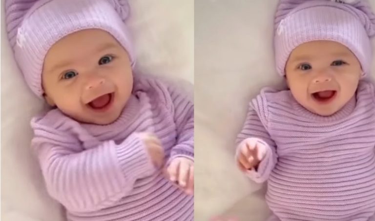 Adorable Baby Girl in Pink Outfit Smiling on Bed